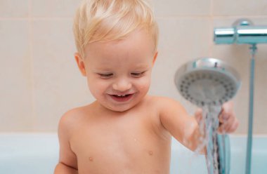 Islak köpük saç uzağa arıyorsunuz ile beyaz banyo oturan küçük meraklı güzel bebek. Bebek banyo sonra kukuletalı bir havlu altında