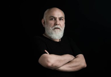 Orta yaşlı erkek. Yaşlı adamın yakın plan portresi siyah üzerine çapraz kollar.