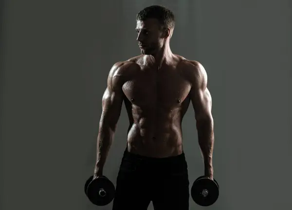 瘦小的躯干 男人与哑铃 肌肉发达的男人在演播室里做运动强壮的男人赤身裸体的腹肌 — 图库照片