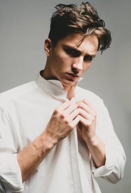 Moda adamı. Yakışıklı, güzel bir erkek model portresi, gri arka planda genç bir adam.