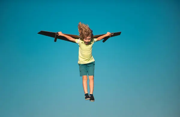 Child boy like a pilot with toy wings against blue sky. Kids freedom concept. Startup