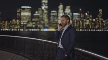 Smartphone Kullanan İşadamı Gece New York Caddesi 'nde Neon ışıklarıyla dolu. Olgun bir iş adamı Manhattan 'da New York caddesinde telefonla konuşuyor. Gece iş konuşmaları