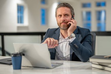 Ofis işyeri. İş adamı iş yerinde telefonla konuşuyor. Klavyede daktilo yazan iş adamı, online iş toplantısı. Ofiste çalışan bir iş adamı. Bilgisayarı kullanan bir ofis çalışanı