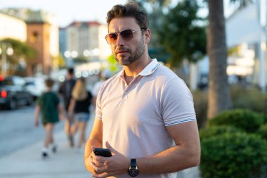 Şehir caddesinde telefonda konuşan yakışıklı bir adam. Büyük şehirde şehir hayatı yaşayan başarılı bir erkek model telefonda konuşuyor. Genç erkek manken dışarıda telefon kullanıyor. İş telefonu görüşmesi