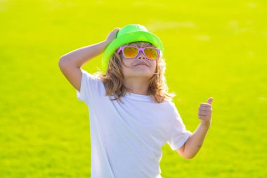 Şapkalı ve güneş gözlüklü yaz çocukları. Dışarıdaki çocuğun portresi. Kapalı yüzlü çocuk yaz parkında dışarıda oynuyor.
