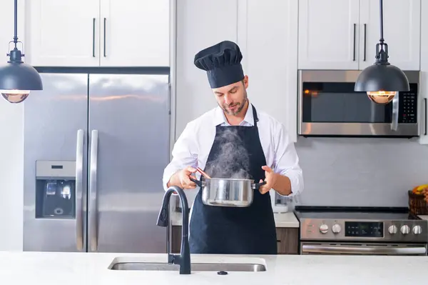 Man chef cooking food in pan pot in kitchen. Process of preparing gourmet dish. Man cooking at home in kitchen, using pot. Chef cooking food. Handsome chef cook cooking concept