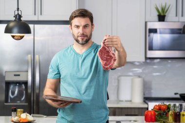 Chef cooking raw meat fillet in the kitchen. Restaurant menu concept. Male portrait of chef man hold meat in the kitchen. Raw meat fillet for advertising