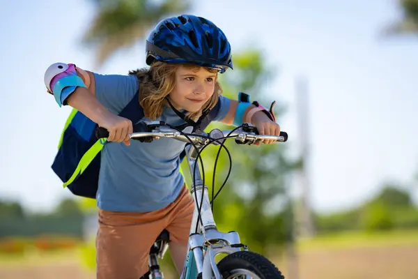 Sporty kid riding bike on a park. Child in safety helmet riding bicycle. Kid learns to ride a bike. Kids on bicycle. Happy child in helmet cycling outdoor. Sports leisure with kids