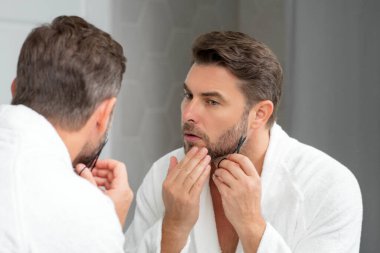 Erkek saç stili, saç kesimi. Elinde makas olan adam. Erkek saç bakımı, güzellik berberi konsepti. Makasla sakallı bir adamın portresi. Tıraşsız adam saçını makasla kesti. Sakal şekillendirme ve makasla kes