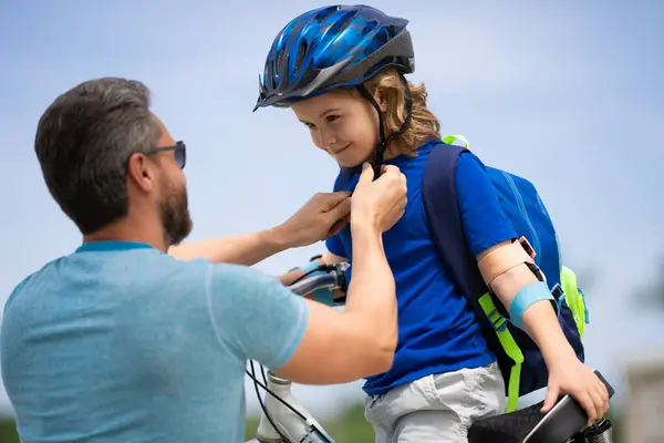 Kids insurance. Father and son concept. Father teaching son riding bike. Father helping his son to wear a cycling helmet. Child in safety helmet.Child in safety helmet learning to ride cycle with dad