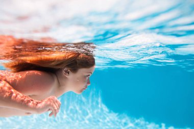 Çocuklar tatil ve yaz tatili konsepti. Çocuk yüzme havuzunda suyun altında yüzüyor. Komik çocuk suratı. Çocuklar deniz suyunda yüzer.