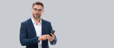Takım elbiseli adam stüdyo arka planında izole edilmiş cep telefonu kullanıyor. Cep telefonu kullanan orta yaşlı bir adamın portresi. Akıllı telefonu olan adam stüdyo geçmişini izole etmiş. Banner, boşluğu kopyala