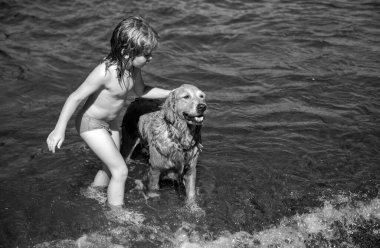 Deniz suyunda köpekle oynayan bir çocuk.