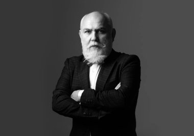 Kıdemli adam. Olgun iş adamı gri kameraya bakıyor.