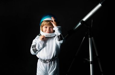 Teleskoplu çocuk kendini uzay kaskı takan bir astronot olarak hayal ediyor. Astronomi ve astroloji kavramı
