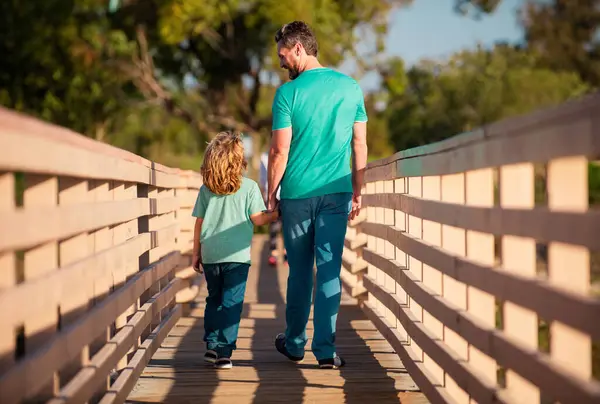 Father with son walking on wooded bridge outdoor