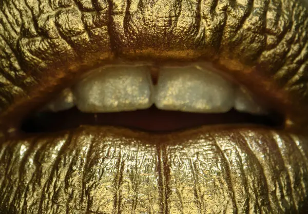 Sexy girl golden lips, gold mouth. Glowing gold skin make-up. Glitter metallic shine golden lipgloss makeup. Golden lips macro close up