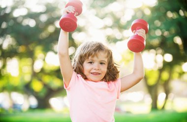 Parkta dambılla antrenman yapan mutlu çocuk. Spor aktivitesi. Çocuk sporu. Çocuk dışarıda egzersiz yapıyor.