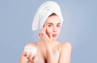 Sakin yüzlü genç bir kadın, banyo prosedürleri, kafaya havlu sarılmış, stüdyo arka planında izole edilmiş. Sabah vakti, hijyen. Spa 'dan sonra. Güzellik tedavisinden sonra mükemmel cilde sahip güzel bir kadın