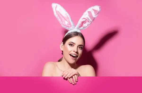 Easter bunny woman with rabbit ears. Beautiful young girl with on pink blank poster