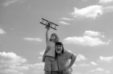 Mavi gökyüzü ve bulutların arkasında oyuncak uçakları olan çocuk ve büyükbaba. Erkekler, büyükbaba ve torun açık havada oynuyorlar.