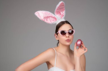 Fashion bunny girl with color egg. Easter eggs hunt. Smiling woman in rabbit ears clipart