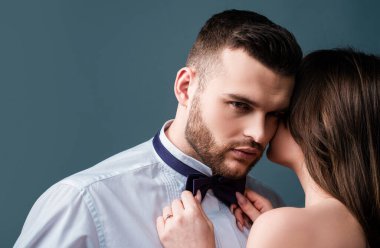 Kadın, erkeğin papyonunu, papyonunu tutuyor. Aşık seksi bir çift. Şehvetli aşıklar soyunur. Kız arkadaş ve erkek arkadaş şehvetli kucaklaşmalar. Erkek kıza romantik kucaklaşma. Şefkatle sarıl. Çıplak tutku vücudu