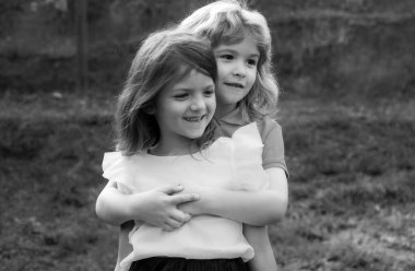 Yaz günü dışarıda sevimli mutlu çocuklar, küçük bir çocuk bir kızı öpüyor. Sevimli küçük kız ve oğlan, dışarıda eğlenin ve sarılın. Komik çocuk suratı