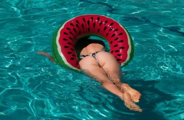 Sexy woman legs and butt in pool. Beautiful woman on inflatable ring at pool