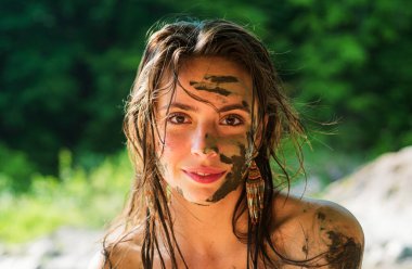 Yüzünde doğal kilden maske olan güzel bir kız.