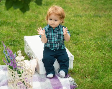 Doğada yeşil çimlerin üzerinde oynayan küçük bir bebek. Çocuklar oynuyor. Bebek ve yaz güneşli hava