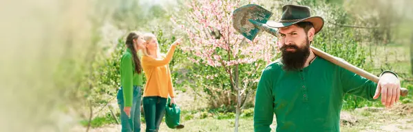 Group of youth work in spring yard with garden tools. A group of friends enjoy the spring nature and take care of the plants. Spring couple in love, banner