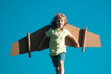 Çocuk karton kanatlarla oynuyor. Geleceğin çocuk rüyası. Çocuk pilot rüya görüyor. Çocuk geleceğin hayalini kuruyor. Çocukluk hayali konsepti. Sarışın, tatlı hayalperest çocuk uçarken rüya görür