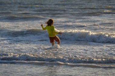 Yaz tatilinde deniz kıyısında koşan bir çocuk. Yaz tatili. Yaz çocukları hafta sonu. Deniz suyundaki çocuk. Yaz eğlencesi. Çocuk denizde yaz tatilinin tadını çıkarıyor. Denizdeki yaz çocuğu