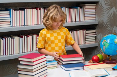 Kitabı olan bir öğrenci. Bir yığın kitabı olan bir öğrenci. Çocuklar okul kütüphanesinde kitap hikayesinin keyfini çıkarıyorlar. Çocukların hayal gücü, edebiyata olan ilgisi. Zeki çocuklar. Sınıfta çocuk eğitimi kitabı okudu