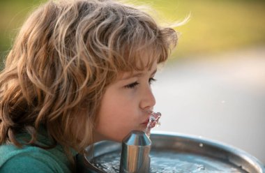 Dışarıdaki çeşmeden su içen çocuk portresini kapatın.