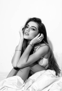 Yatakta rahatlayan güzel, şehvetli bir kadının portresi. Genç bir kadın beyaz yatak odasında yalnız eğleniyor.