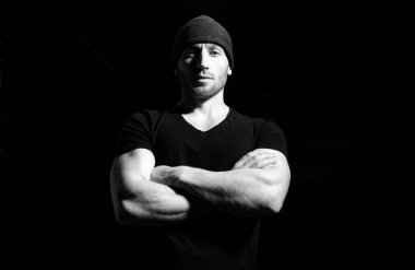 Kollarını kavuşturmuş genç ve seksi bir adamın portresi. Siyah stüdyoda erkek model.