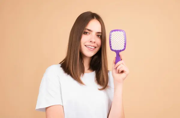 Brushing Hair. Portrait young woman brushing straight natural hair with comb. Girl combing hair with hairbrush. Hair care beauty concept