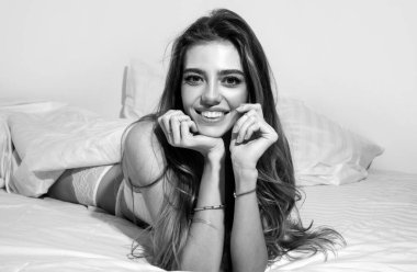 Gülümseyen güzel kadın yatak odasındaki yorganın altında yatıyor.