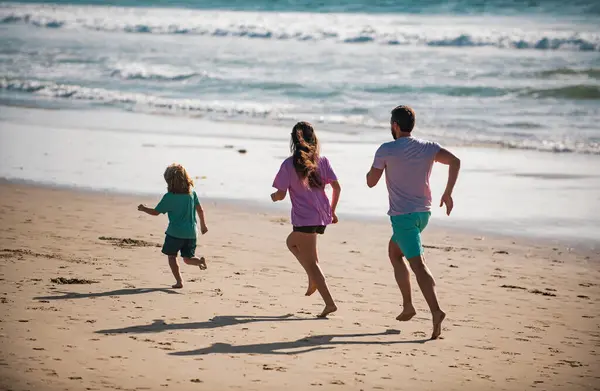 Father, mother and child running jogging on the beach. Concept healthy family lifestyle. Summer people vacation at sea