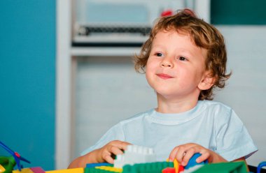 İlkokuldan bir çocuk. Çocuk anaokulundaki oyuncaklarla oynuyor.