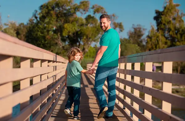 Father with son walking on wooded bridge outdoor