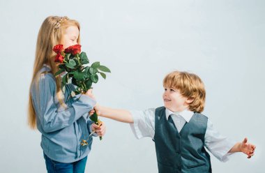 Little Boy with a rose for his teen girlfriend, romantic children, isolated on white background. Little boy giving flowers to girl. Love concept