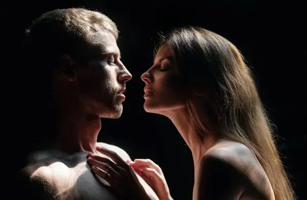 Man embracing and going to kiss sensual woman. Loving couple kissing over black background. Real love on Valentines Day