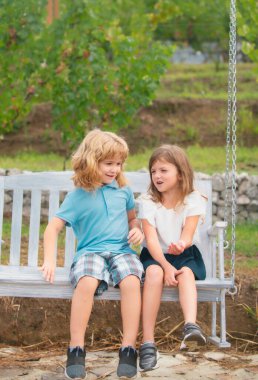 Brother and sister playing in spring park outdoors. Little boy and girl kids enjoying spring. Kids walking at backyard. Best friends two children