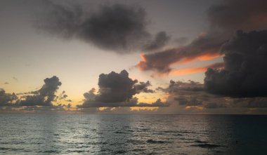 Denizde gün batımı. Sakin bulutlu gökyüzü ile okyanus sahili gündoğumu