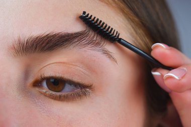 Mükemmel kaşlar. Kadının kaş makyajı yaptırmasına yakın çekim. Fırçalı makro kaş. Mükemmel bir kaş şekli, kahverengi göz farı ve uzun kirpikleri. Kaş şekilli. Keskin kaşlar