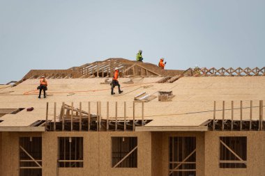 Çatıda çatı tamiri var. İnşaat işçisi yeni çatı döşedi. Büyük bir çatı katı inşaatında inşaat işçisi. Çatı marangozu çatı inşaat alanında çalışıyor.