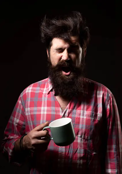 Bearded man yawning hold mug tea. Wake up. Morning tea. Man with cup. Man yawning with cup of coffee. Bearded guy yawning, hold mug tea. Good morning. After tea. Yawning face
